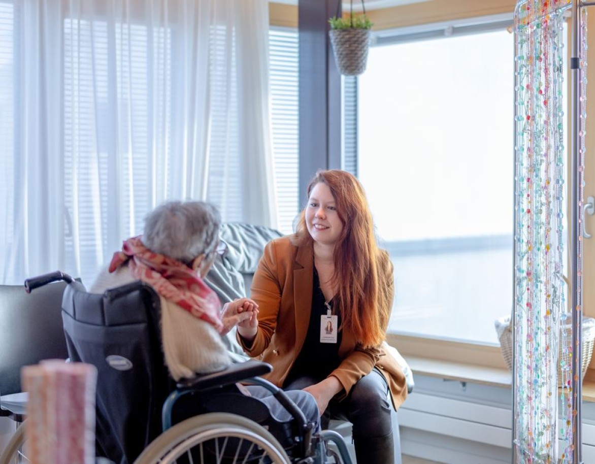 Accompagnatrice tient la main d'une résidente en fauteuil